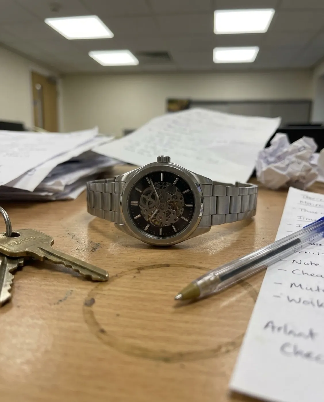 Armbanduhr als Handyfoto auf unaufgeräumtem Schreibtisch (vorher)